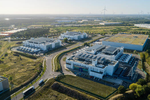 Aerial view of Vantage Data Centers BER1 facility featuring modern industrial buildings and cooling units in the surrounding green landscape in Ludwigsfelde Brandenburg Germany. Aerial view of Vantage Data Centers BER1 facility featuring modern industrial buildings and cooling units in the surrounding green landscape in Ludwigsfelde Brandenburg Germany.