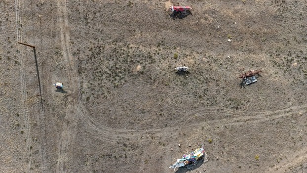 Aerial view of scattered debris and art installations in a dry open field with a utility pole and dirt tracks in Golden Colorado United States.