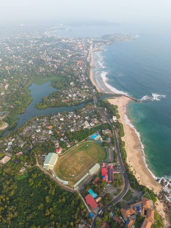 Aerial view of the coastline featuring a sports stadium sandy beaches and lush tropical greenery in Galle Southern Province Sri Lanka.