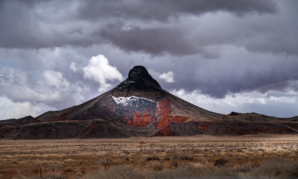 View of Monument Valley Tribal Park with a snow dusted butte rising above the desert floor under a dramatic stormy sky in Oljato Monument Valley Utah United States.