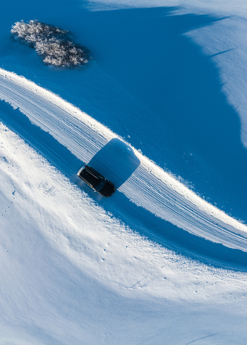 Aerial view of a car driving along a snow covered road through a winter landscape in Latvia. Aerial view of a car driving along a snow covered road through a winter landscape in Latvia.