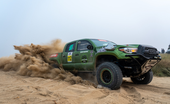 Kot Addu Pakistan 08 November 2024 View of the Thal Jeep Rally featuring a green Toyota pickup truck racing through the desert and kicking up a large cloud of sand.