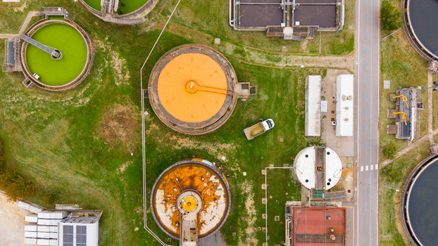 Aerial view of the wastewater treatment plant with circular sedimentation tanks green and orange basins and surrounding grassy areas in Rancate Lombardia Italy.
