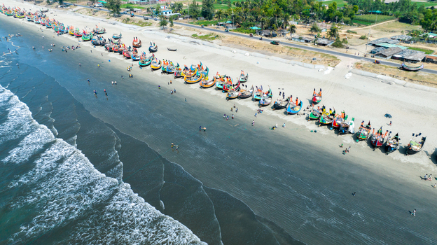 Aerial view of colorful fishing boats dotting the shoreline where the sandy beach meets the turquoise sea Cox s Bazar Chittagong Division Bangladesh. Aerial view of colorful fishing boats dotting the shoreline where the sandy beach meets the turquoise sea Cox s Bazar Chittagong Division Bangladesh.