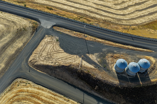 Aerial view of three grain silos situated near a rural road intersection surrounded by golden wheat fields in Palouse Washington United States. Aerial view of three grain silos situated near a rural road intersection surrounded by golden wheat fields in Palouse Washington United States.