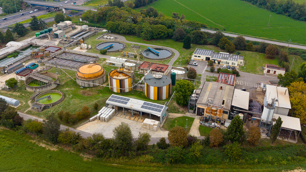 Aerial view of the wastewater treatment plant featuring circular sedimentation tanks industrial storage silos and surrounding green fields near a highway in Rancate Lombardia Italy. Aerial view of the wastewater treatment plant featuring circular sedimentation tanks industrial storage silos and surrounding green fields near a highway in Rancate Lombardia Italy.