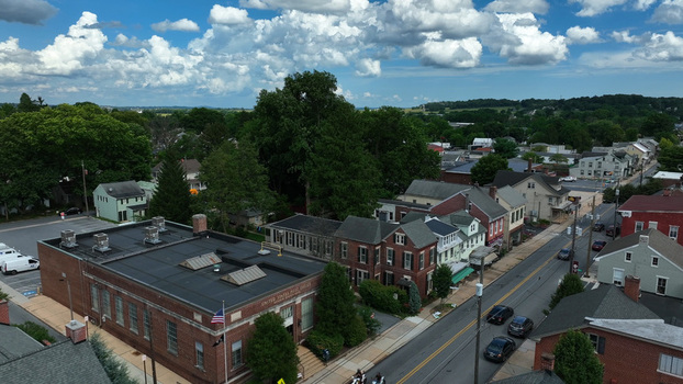 Aerial view of the United States Post Office building surrounded by historic brick houses lush green trees and a quiet street in Manheim Pennsylvania United States.