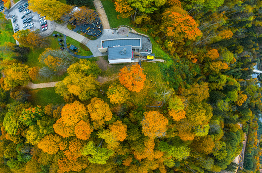 Aerial view of Sigulda park area with vibrant autumn foliage a modern building and a parking lot surrounded by dense trees in Sigulda Sigulda Municipality Latvia. Aerial view of Sigulda park area with vibrant autumn foliage a modern building and a parking lot surrounded by dense trees in Sigulda Sigulda Municipality Latvia.