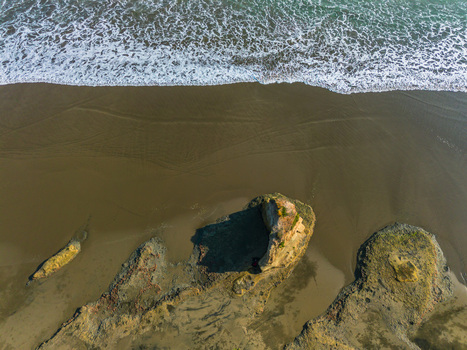 Aerial view of sandy beach with unique rock formations and ocean waves washing onto the shore in Bali Bali Indonesia. Aerial view of sandy beach with unique rock formations and ocean waves washing onto the shore in Bali Bali Indonesia.