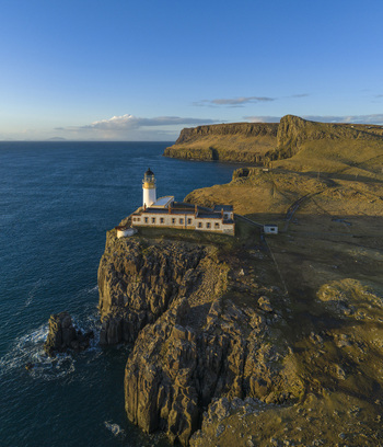 Aerial view of Neist Point Lighthouse perched on a dramatic rocky cliff overlooking the blue Atlantic Ocean under a clear sky Isle of Skye Scotland United Kingdom. Aerial view of Neist Point Lighthouse perched on a dramatic rocky cliff overlooking the blue Atlantic Ocean under a clear sky Isle of Skye Scotland United Kingdom.