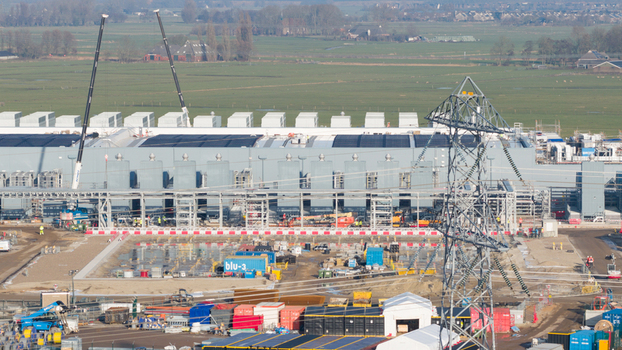 Groningen Netherlands 20 January 2026 Aerial view of Datacenter Westpoort with cooling units construction cranes and a power pylon against flat green fields.