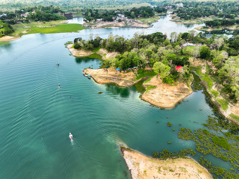 Rangamati Hill District Chittagong Division Bangladesh 18 May 2024 Aerial view of Kaptai Lake with boats on turquoise water surrounded by lush green hills and scattered rural dwellings.