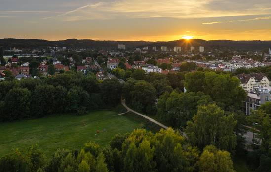 Aerial view of Sopot at sunset featuring lush green parks residential buildings and dense trees under a golden sky in Sopot Pomeranian Voivodeship Poland. Aerial view of Sopot at sunset featuring lush green parks residential buildings and dense trees under a golden sky in Sopot Pomeranian Voivodeship Poland.