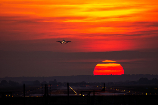 View of an airplane approaching the runway at Bucharest Henri Coanda International Airport during a vibrant sunset with glowing runway lights in Otopeni Judetul Ilfov Romania. View of an airplane approaching the runway at Bucharest Henri Coanda International Airport during a vibrant sunset with glowing runway lights in Otopeni Judetul Ilfov Romania.