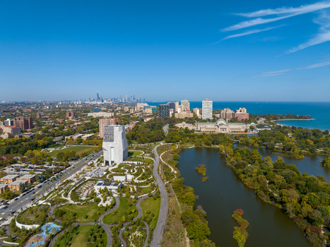 Aerial view of The Obama Presidential Center surrounded by parkland and winding paths with the Chicago skyline and Lake Michigan in the distance Chicago Illinois United States. Aerial view of The Obama Presidential Center surrounded by parkland and winding paths with the Chicago skyline and Lake Michigan in the distance Chicago Illinois United States.