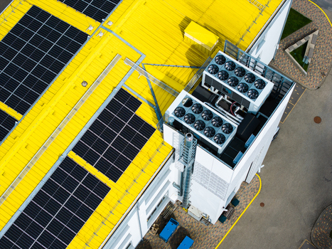 Aerial view of a modern building with a vibrant yellow roof featuring solar panels and rooftop HVAC units in Valdlauci Kekava Municipality Latvia. Aerial view of a modern building with a vibrant yellow roof featuring solar panels and rooftop HVAC units in Valdlauci Kekava Municipality Latvia.