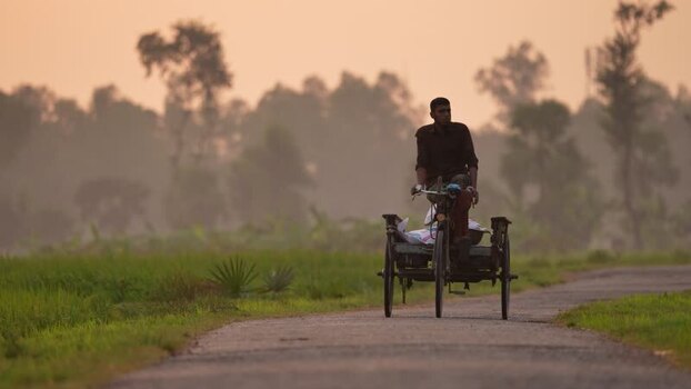View of a man riding a cycle van on a rural road Bangladesh.
