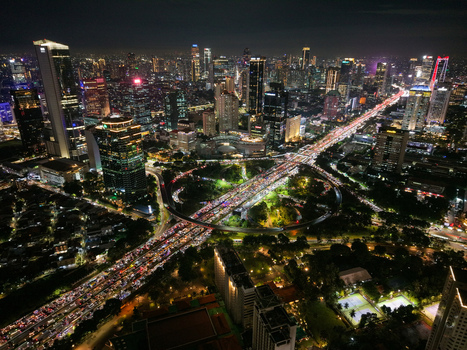 Aerial view of Semanggi Interchange at night with heavy traffic flowing through the iconic cloverleaf junction surrounded by skyscrapers and city lights in Setiabudi Jakarta Indonesia. Aerial view of Semanggi Interchange at night with heavy traffic flowing through the iconic cloverleaf junction surrounded by skyscrapers and city lights in Setiabudi Jakarta Indonesia.