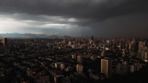 Aerial view of the sprawling Mexico City skyline under dramatic dark storm clouds with high rise buildings and distant mountains in Mexico City Mexico City Mexico.