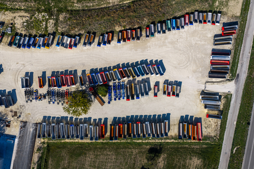 Aerial view of numerous colorful semi truck trailers parked in an organized industrial lot with gravel ground and a small tree in Spoleto Umbria Italy. Aerial view of numerous colorful semi truck trailers parked in an organized industrial lot with gravel ground and a small tree in Spoleto Umbria Italy.