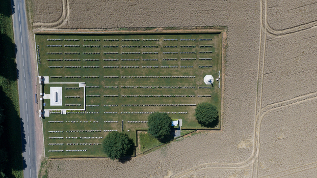 Aerial view of Delville Wood Cemetery with rows of white headstones set in green grass surrounded by agricultural fields in Longueval Hauts de France France.
