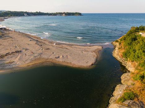 Aerial view of Kiten South Beach where the river meets the Black Sea featuring sandy shores rocky cliffs and calm coastal waters in Kiten Burgas Bulgaria. Aerial view of Kiten South Beach where the river meets the Black Sea featuring sandy shores rocky cliffs and calm coastal waters in Kiten Burgas Bulgaria.