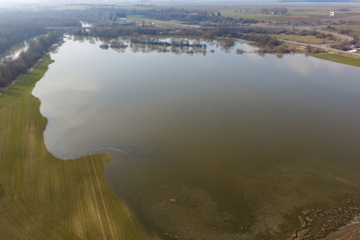 Aerial view of flooded green fields and bare trees near a river under a hazy sky in Kaniukai Kaunas County Lithuania. Aerial view of flooded green fields and bare trees near a river under a hazy sky in Kaniukai Kaunas County Lithuania.