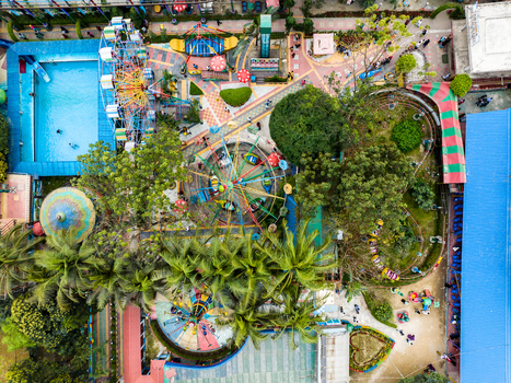 Aerial view of an amusement park featuring a Ferris wheel swimming pool various rides lush palm trees and paved pathways in Dhaka Dhaka Division Bangladesh. Aerial view of an amusement park featuring a Ferris wheel swimming pool various rides lush palm trees and paved pathways in Dhaka Dhaka Division Bangladesh.