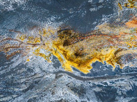 Aerial view of the vibrant mineral rich riverbed featuring striking yellow and orange deposits contrasted against dark cracked earth patterns in Andalusia Spain. Aerial view of the vibrant mineral rich riverbed featuring striking yellow and orange deposits contrasted against dark cracked earth patterns in Andalusia Spain.
