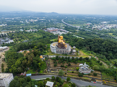Aerial view of the large golden Buddha statue overlooking the lush green landscape and surrounding temple grounds in Jiuru Township Pingtung County Taiwan. Aerial view of the large golden Buddha statue overlooking the lush green landscape and surrounding temple grounds in Jiuru Township Pingtung County Taiwan.