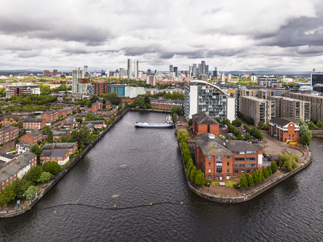 Aerial view of MediaCityUK and the Manchester Ship Canal in Salford featuring modern apartment buildings red brick architecture and the distant city skyline. Salford England United Kingdom. Aerial view of MediaCityUK and the Manchester Ship Canal in Salford featuring modern apartment buildings red brick architecture and the distant city skyline. Salford England United Kingdom.