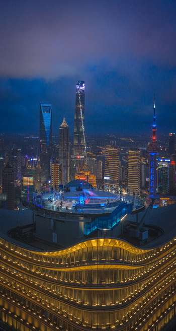 Aerial view of the illuminated Shanghai Baiyulan Plaza helipad overlooking the Pudong skyline with the Shanghai Tower and Oriental Pearl Tower at night Shanghai Shanghai China.