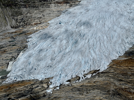 Aerial view of the Svartisen glacier in Saltfjellet Svartisen National Park showcasing intricate ice crevasses rugged rocky terrain and glacial meltwater in Rana Municipality Nordland Norway.
