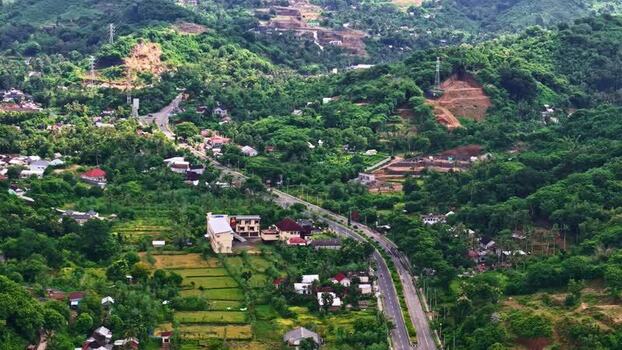 Aerial view of winding road through lush hills in Indonesia.