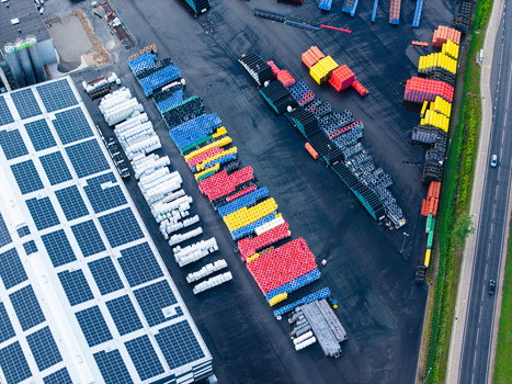 Aerial view of a manufacturing facility showcasing organized rows of colorful polymer pipes and a large warehouse roof covered with solar panels in Jelgava Latvia. Aerial view of a manufacturing facility showcasing organized rows of colorful polymer pipes and a large warehouse roof covered with solar panels in Jelgava Latvia.