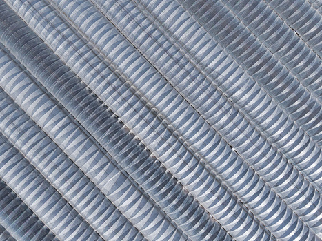 Aerial view of corrugated metal roofing a textured landscape of repeating curves and shadows creating an abstract architectural pattern Stafford England United Kingdom. Aerial view of corrugated metal roofing a textured landscape of repeating curves and shadows creating an abstract architectural pattern Stafford England United Kingdom.