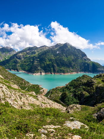 View of the turquoise waters of Lac d Emosson surrounded by rugged mountains and lush alpine vegetation at VerticAlp Emosson Le Chatelard Fribourg Switzerland. View of the turquoise waters of Lac d Emosson surrounded by rugged mountains and lush alpine vegetation at VerticAlp Emosson Le Chatelard Fribourg Switzerland.