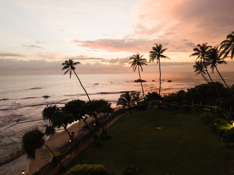 Aerial view of Gintota beach with palm trees and ocean waves under a sunset sky in Galle Southern Province Sri Lanka. Aerial view of Gintota beach with palm trees and ocean waves under a sunset sky in Galle Southern Province Sri Lanka.
