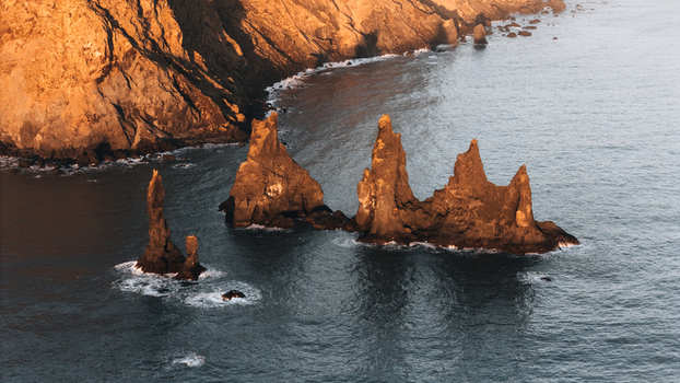 Aerial view of jagged basalt sea the turbulent sea casting long shadows over the water at Reynisdrangar Iceland.
