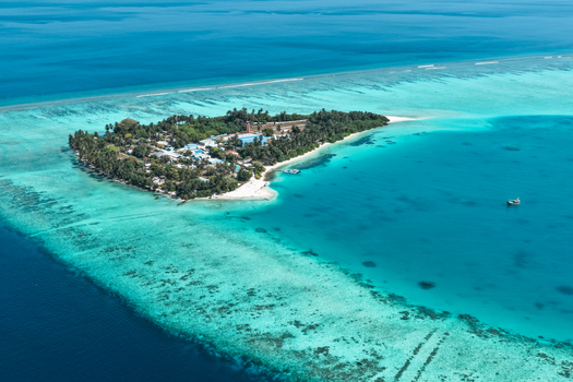Aerial view of Vaanee island surrounded by turquoise lagoon waters coral reefs and lush tropical vegetation in Vaanee Dhaalu Atoll Maldives. Aerial view of Vaanee island surrounded by turquoise lagoon waters coral reefs and lush tropical vegetation in Vaanee Dhaalu Atoll Maldives.