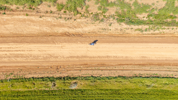 Aerial view of a cyclist riding along a dusty dirt road through green rural fields in Greyton Western Cape South Africa.