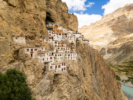 Aerial view of Phukthal Gompa a historic Buddhist monastery built into the side of a cliff overlooking a river valley with rugged mountain terrain in Phukthal Ladakh India.