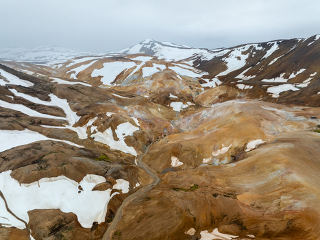 Aerial view of the colorful rhyolite mountains of Kerlingarfjoll with patches of snow and rugged volcanic terrain in Hrunamannahreppur Iceland. Aerial view of the colorful rhyolite mountains of Kerlingarfjoll with patches of snow and rugged volcanic terrain in Hrunamannahreppur Iceland.