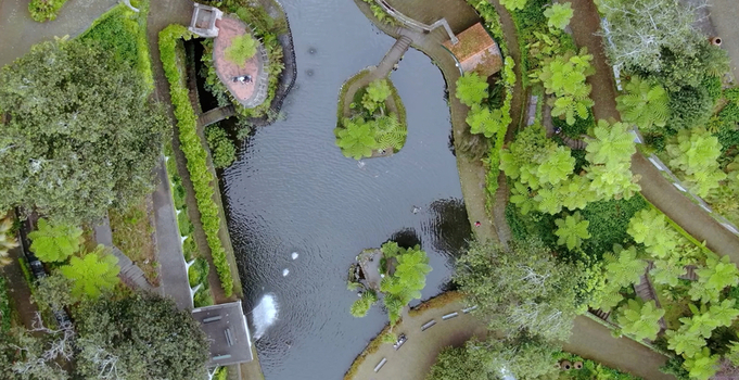 Aerial view of the Monte Palace Tropical Garden featuring a central pond with small islands lush green vegetation and winding pathways in Funchal Madeira Portugal. Aerial view of the Monte Palace Tropical Garden featuring a central pond with small islands lush green vegetation and winding pathways in Funchal Madeira Portugal.