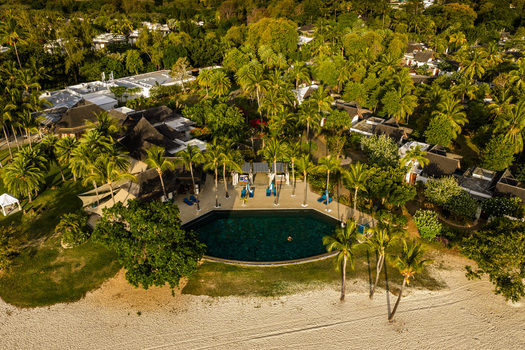Aerial view of a luxury tropical resort featuring a dark swimming pool surrounded by palm trees and a white sand beach Moka District Mauritius. Aerial view of a luxury tropical resort featuring a dark swimming pool surrounded by palm trees and a white sand beach Moka District Mauritius.