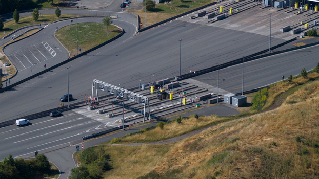 Aerial view of Gare de Peage de Dury toll plaza with vehicles passing through lanes surrounded by grassy slopes and road infrastructure in Saleux Hauts de France France.