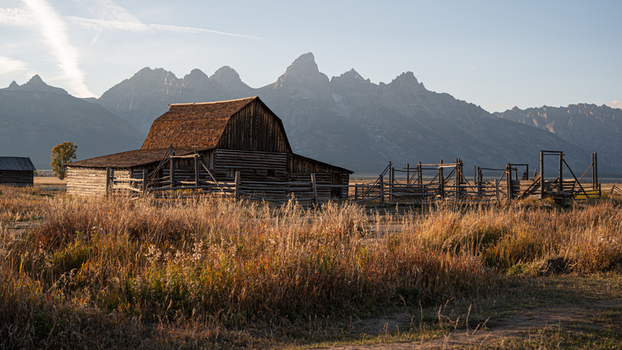View of the historic Moulton Barn in Jackson Hole with the Teton mountain range in the background under golden hour light in Teton County Wyoming United States.