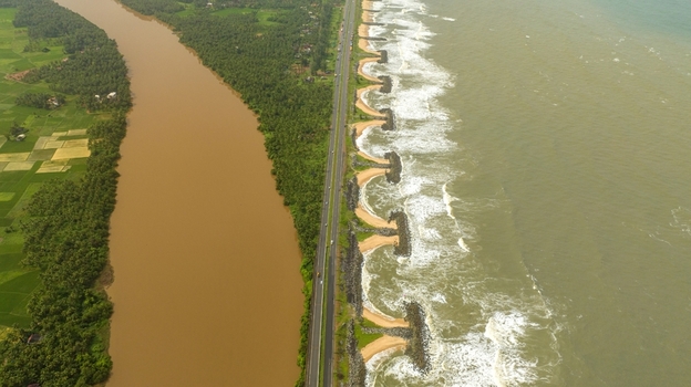 Aerial view of Maravanthe beach featuring the Arabian Sea on one side and the Souparnika River on the other separated by a coastal highway in Maravanthe Karnataka India. Aerial view of Maravanthe beach featuring the Arabian Sea on one side and the Souparnika River on the other separated by a coastal highway in Maravanthe Karnataka India.