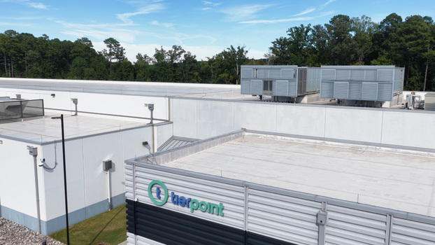 Aerial view of the TierPoint data center facility featuring white rooftops industrial HVAC units and surrounding trees in the United States. Aerial view of the TierPoint data center facility featuring white rooftops industrial HVAC units and surrounding trees in the United States.