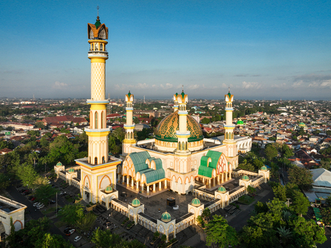 Aerial view of the Islamic Center NTB Hubbul Wathan Great Mosque with its green dome and minaret set within the urban landscape of Kecamatan Selaparang Nusa Tenggara Barat Indonesia. Aerial view of the Islamic Center NTB Hubbul Wathan Great Mosque with its green dome and minaret set within the urban landscape of Kecamatan Selaparang Nusa Tenggara Barat Indonesia.